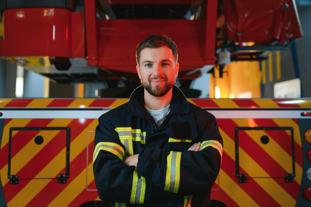 Firefighter in uniform and helmet near fire engine